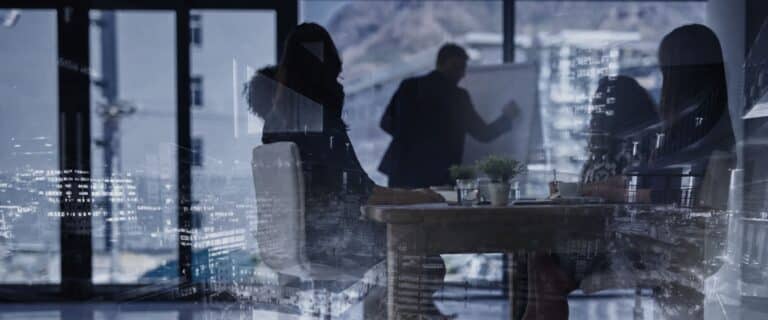 Silhouetted professionals in a glass-walled conference room, with a city skyline and digital data reflections on the glass.
